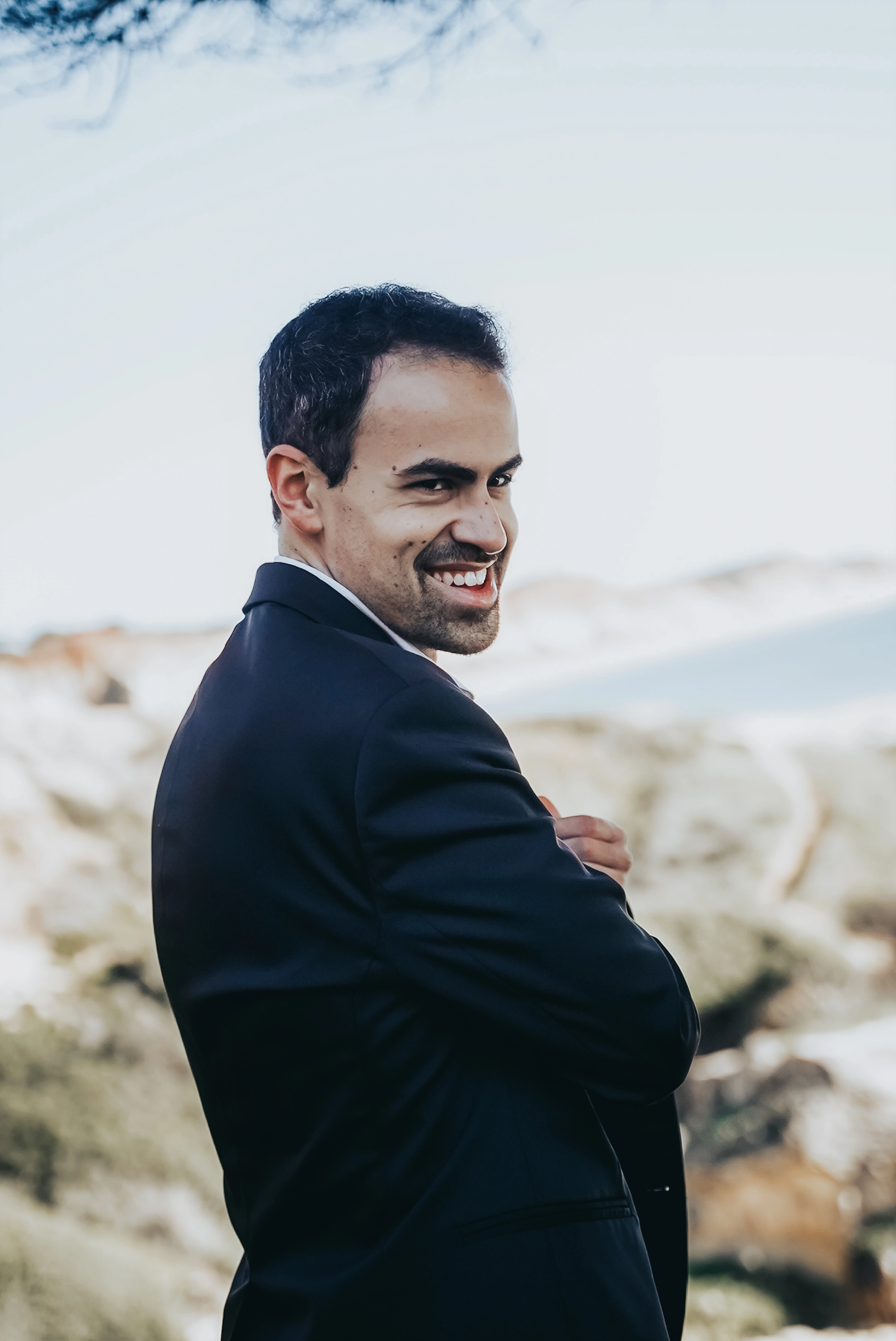 Portrait of E. Sousa wearing a black suit with Praia da Falésia in the background
