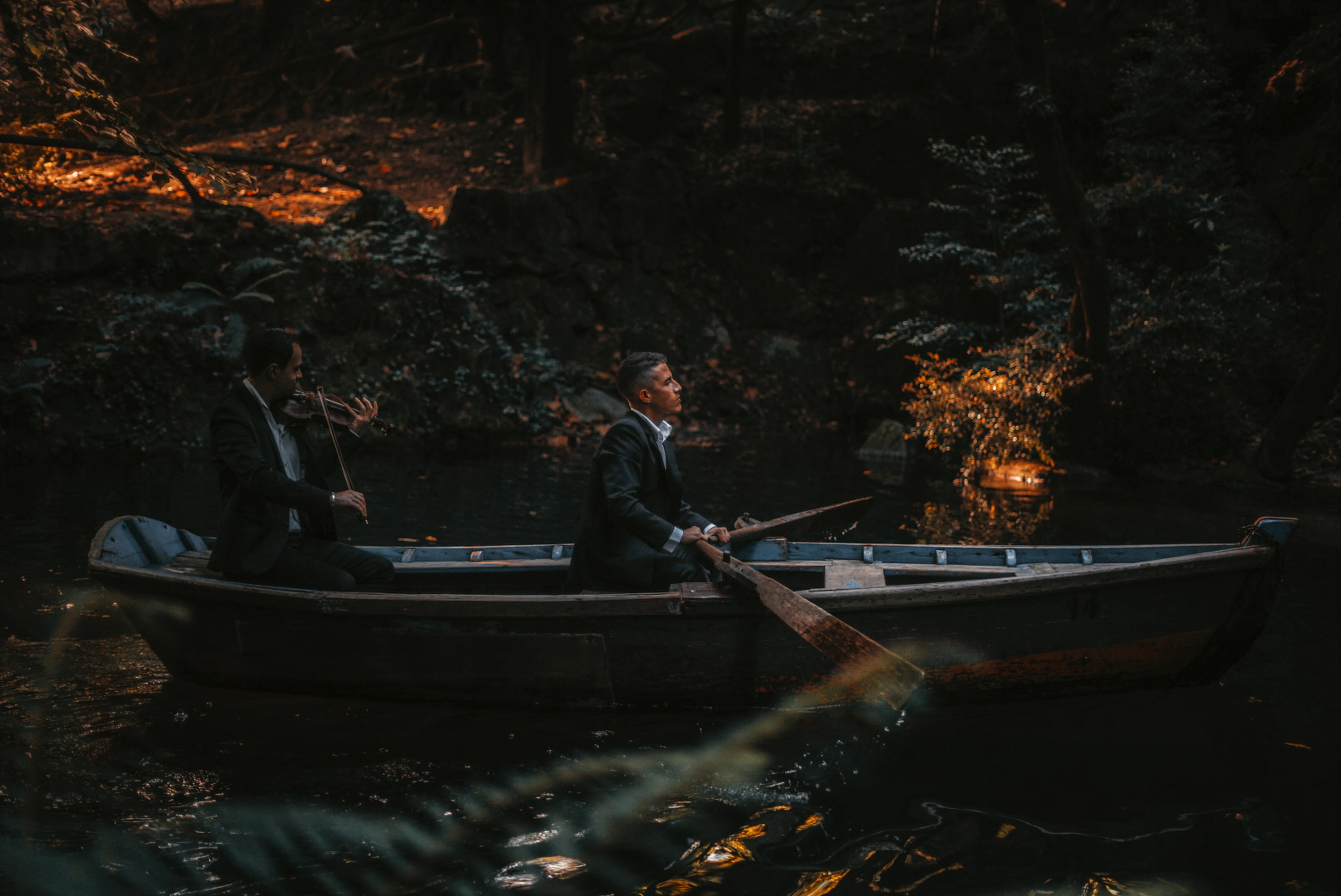 Rafael Xavier rowing a canoe while E. Sousa plays violin on Bom Jesus lake in Braga, Portugal, during the production of the music video Só Hoje Vi